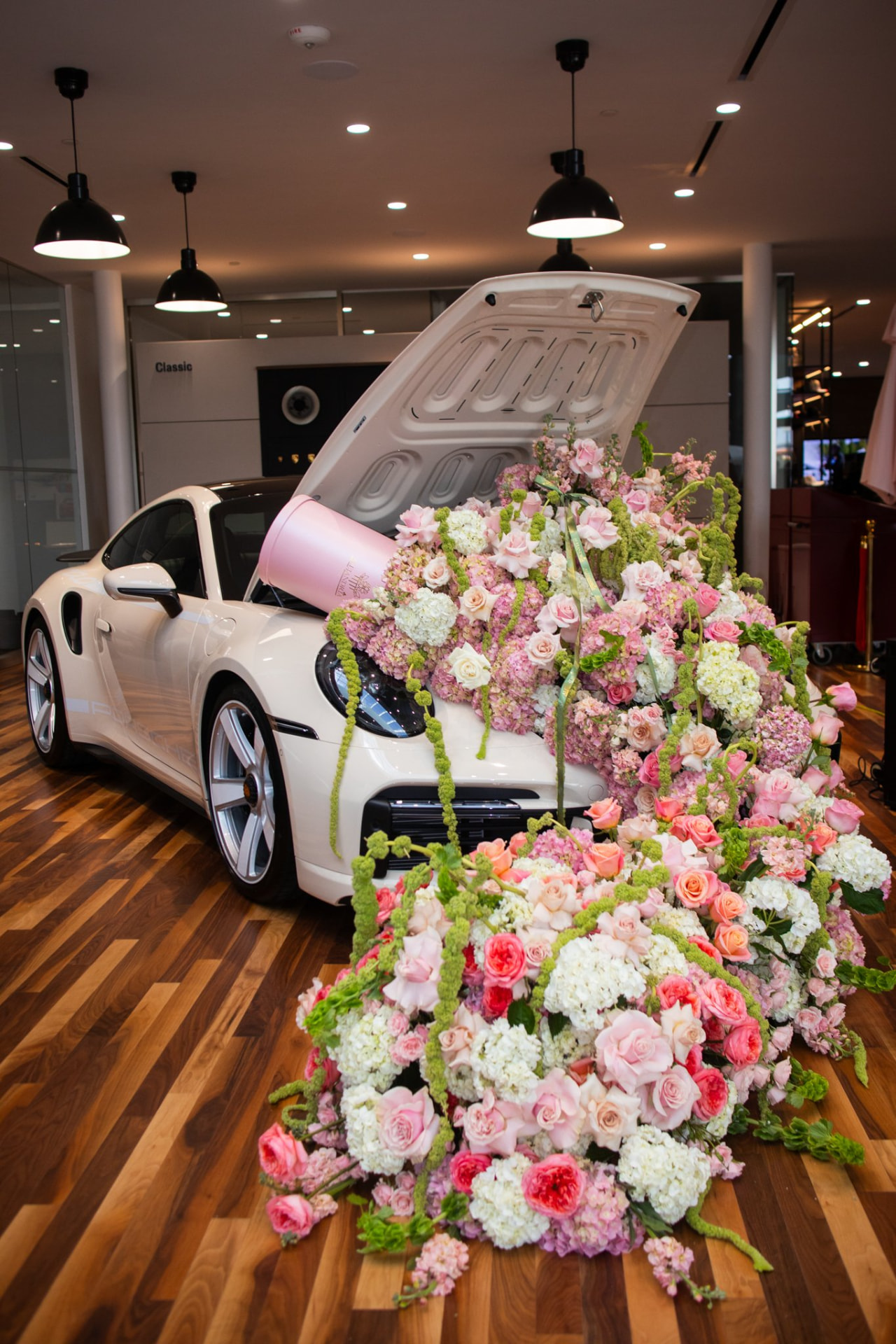 White Porsche 911 with a floral installation spilling from its hood